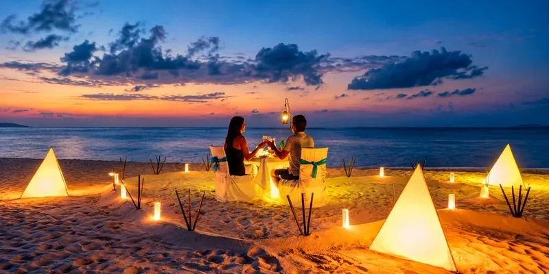 A couple enjoying a candlelit dinner on the beach at dusk