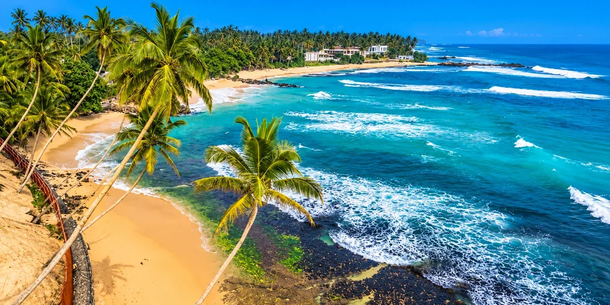Palm-lined sandy coastline and turquoise ocean waters at Unawatuna