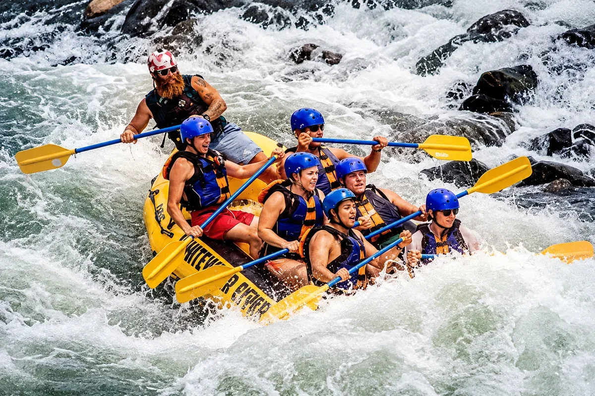 A group wearing helmets and life jackets rafting through white water near Kitulgala