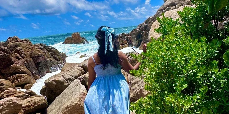 A visitor overlooking the ocean from a rocky tropical coastline