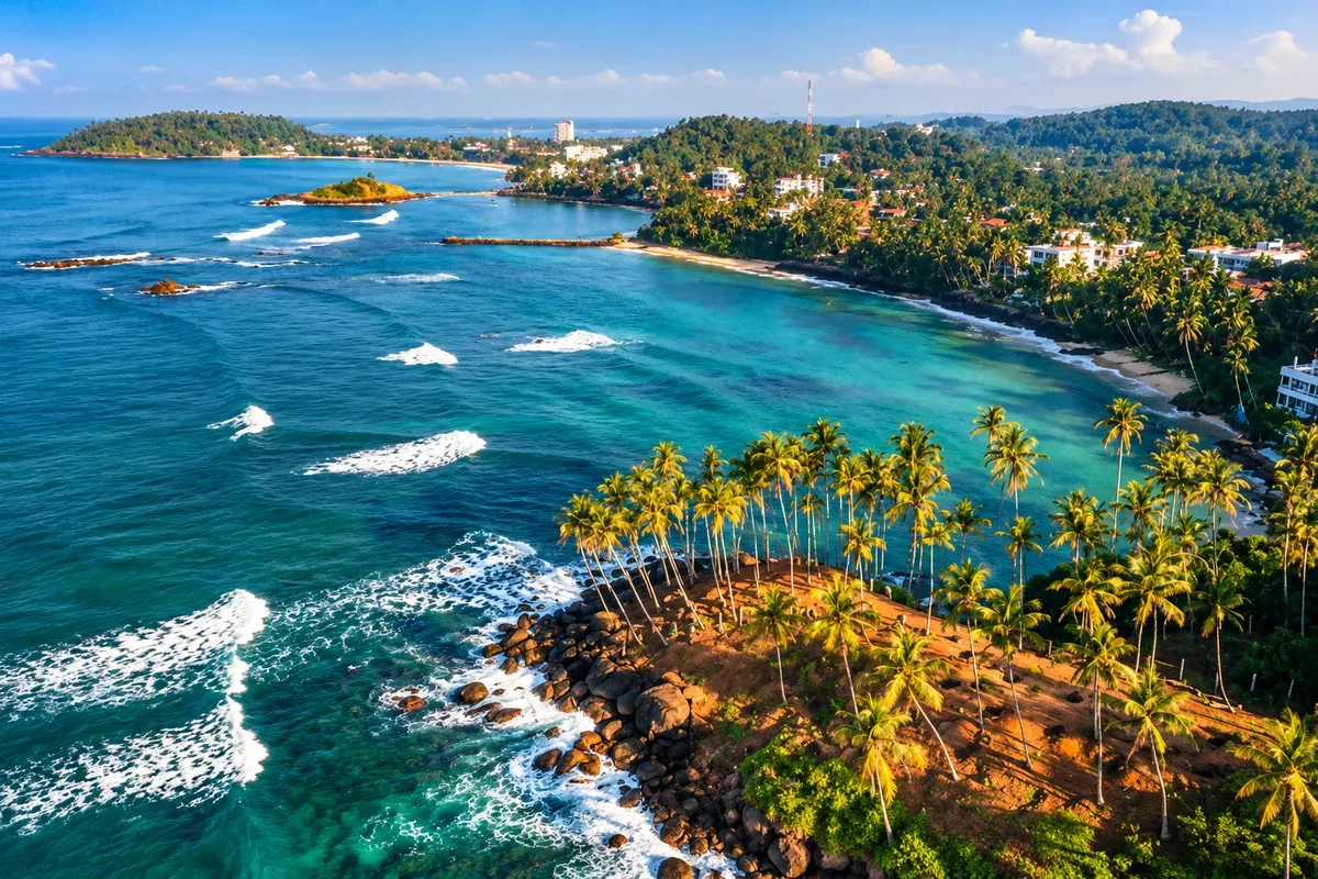 Aerial view of a palm-covered headland and the blue sea in Mirissa