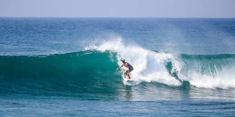 A surfer riding a turquoise wave at Arugam Bay